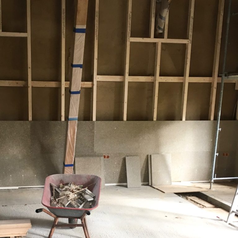 System Innendämmung Baustelle mit Schubkarre, Holzlatten und unvollendeten Wänden.