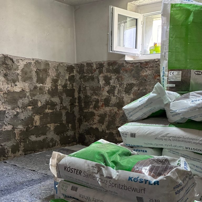 Rohbau mit freiliegendem Ziegelmauerwerk und Baustellenausrüstung im Hintergrund.