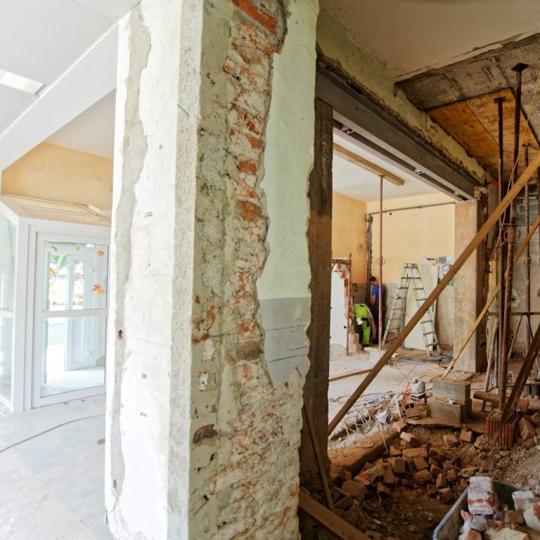 Rohbau mit freiliegendem Ziegelmauerwerk und Baustellenausrüstung im Hintergrund.