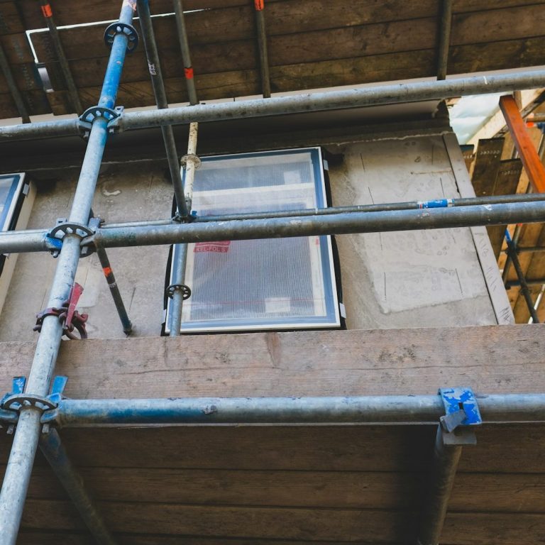 Haus, Baustelle, Gerüst und Materialien vor dem Eingangsbereich.