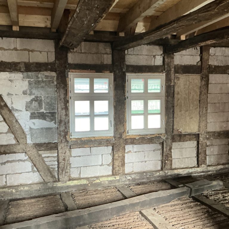 Haus, Baustelle, Gerüst und Materialien vor dem Eingangsbereich.